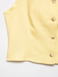 Close-up of yellow vest with marble textured buttons and clean stitching details