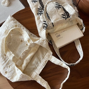Detail of vintage lace embroidered tote bags with intricate patterns on a wooden table