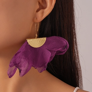 Close-up of model wearing oversized purple chiffon floral earrings with hammered gold metal