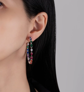 Detailed view of large silver hoops featuring multi-color stones worn by a model