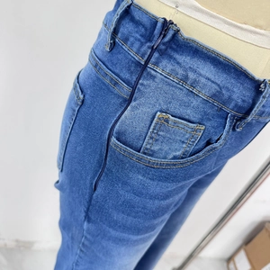 Detail of waist side zipper and pocket stitching on blue wide-leg denim jeans