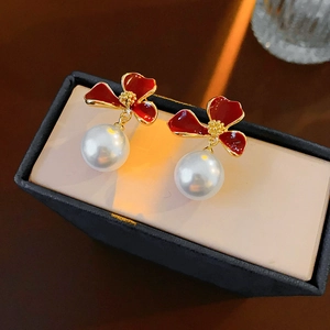 Close-up of vintage flower pearl earrings with red enamel petals and gold frame details