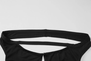 Détail de la robe noire en maille avec une bretelle horizontale et un bouton au col