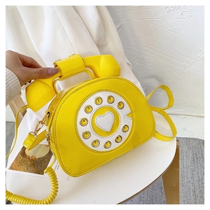 Detailed macro of a yellow vintage telephone crossbody bag with dial and gold hardware