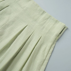 Detail view of cotton vest and shorts set with side zipper and pleated waist in lime green