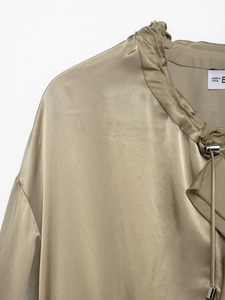 Close-up of golden satin top featuring ruffled neckline and adjustable drawstring detail
