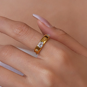 Close-up of golden ring set with drop-shaped and square yellow zircons on finger