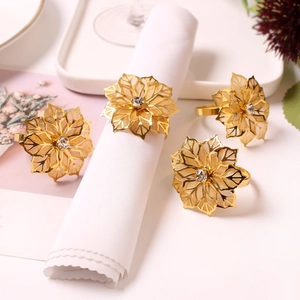 Detail of gold flower napkin rings with rhinestones on a white linen napkin
