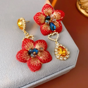 Gros plan sur les boucles d'oreilles asymétriques en tissu rouge avec gouttes jaunes