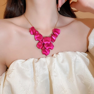 Detail of rose red petal tassel necklace with gold chain worn on a white blouse