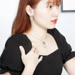 Close-up of a silver stainless steel jewelry set with double ring rhinestone pendants