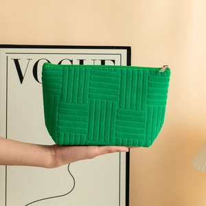Macro detail of vibrant green waffle-textured cosmetic bag held in hand for scale