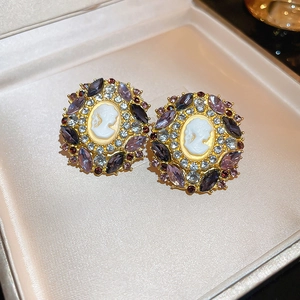Detail of vintage cameo earrings featuring purple crystals and gold-tone portrait relief