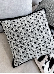 Close-up of black and white velvet braided throw pillow with detailed woven texture on sofa