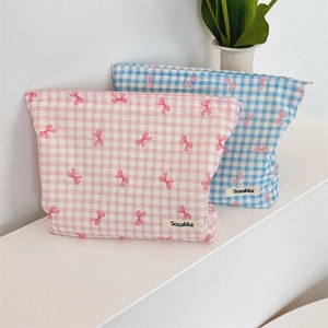 Detail of floral plaid cosmetic bags in pink and blue with bow accents and zippers