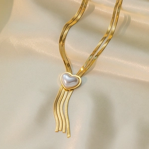 Detail of 18K gold snake chain necklace with heart pearl pendant and elegant tassels