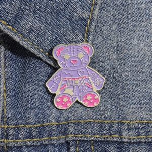 Detail of cute purple cartoon bear enamel pin attached to blue denim jacket fabric