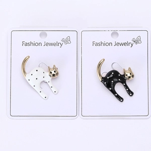 Macro detail of alloy enamel spotted cat brooches in black and white on card
