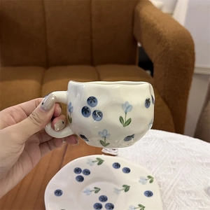 Hand-painted blue floral ceramic coffee cup with irregular wave edges on lace cloth