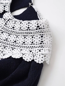 Detailed close-up of navy knit fabric with white crochet lace and metal buckle detail