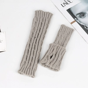 Close-up of grey cable knit arm warmers with thumb hole detail on a white surface