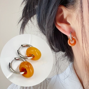 Macro detail of gold-plated hoop earrings with amber resin charm and model shot