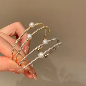 Detail of stacked double-layer gold and silver bangles with pearls and sparkling zircons