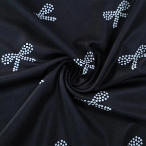 Detail view of black fabric with white polka dot bow patterns and soft pleated texture