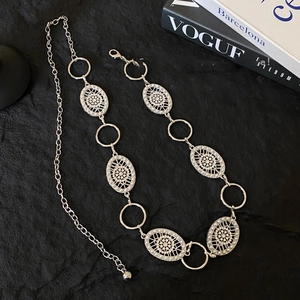 Detail of silver metal waist chain with hollow oval links and delicate pearl accents