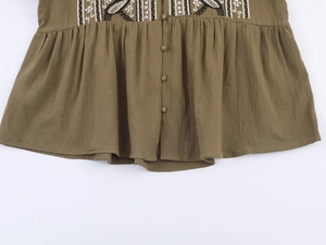 Détail d'une chemise en lin vert olive avec broderie ethnique et boutons en tissu