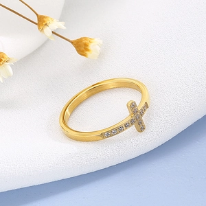 Vue macro d'une bague croix dorée avec zircons et texture en métal brossé