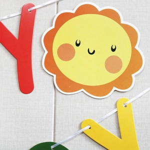 Close-up of daisy macaron birthday banner with letters and cartoon sun decoration