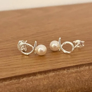 Elegant 925 sterling silver pearl stud earrings with minimalist knot design on wood