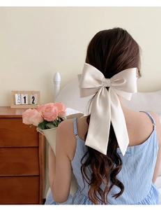 Macro view of large cream white satin bow hair clip on model back of head hairstyles