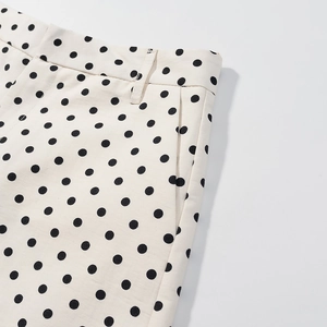 Detailansicht der cremefarbenen Shorts mit schwarzen Punkten, Gürtelschlaufen und Taschen