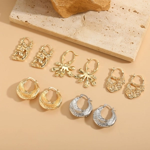 Detailed set of 5 pairs of geometric gold and silver earrings on a stone base