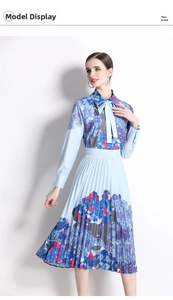 Detail view of long-sleeve pleated dress featuring blue floral patterns and a neck bow tie