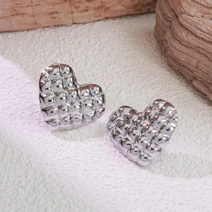 Close-up of heart-shaped silver titanium studs with quilted geometric texture