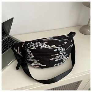 Detail of black crossbody bag featuring vibrant colorful zigzag embroidery and large buckle