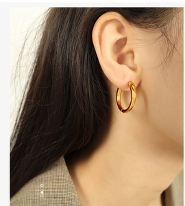 Close-up of polished gold hoop earring worn by a model in a minimalist style