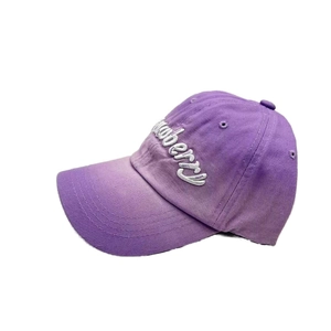 Detail of white strawberry embroidery on purple washed cotton twill baseball cap