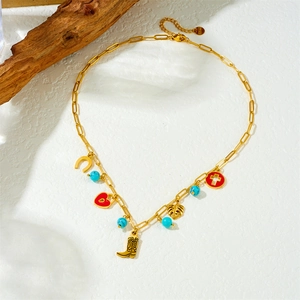 Gold paperclip chain necklace with vintage red heart cross and boot charms on white background