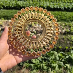 Close-up of golden metal circular wall decor with amber stones and radial pattern