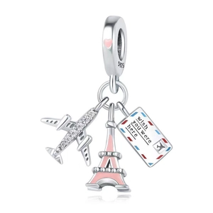 Macro shot of silver airplane, pink Eiffel Tower, and wish you were here postcard charm