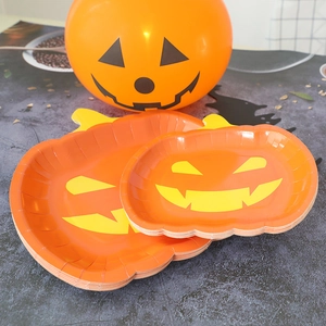 Close-up of Halloween party supplies showing orange pumpkin paper plates and balloons