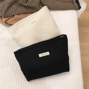 Macro detail of woven textured cosmetic bags in classic black and cream white colors