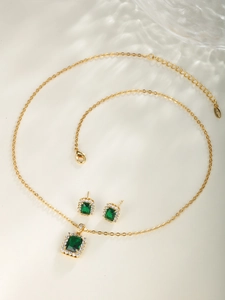 Detail of elegant gold jewelry set with square emerald stone and clear zircon crystals