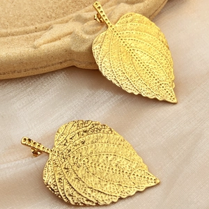 18K gold plated stainless steel leaf earrings with realistic veins on a textured tray