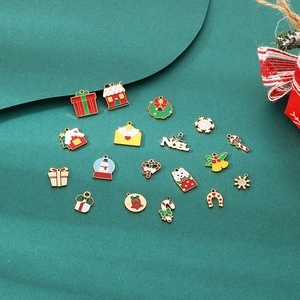 Close-up of 17 Christmas themed stainless steel charms on green fabric for DIY jewelry