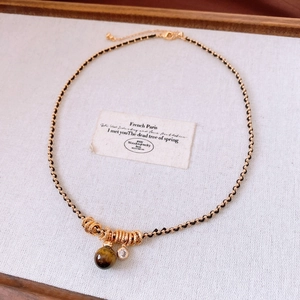 Detail shot of vintage tiger eye stone gourd necklace with golden metal and woven cord